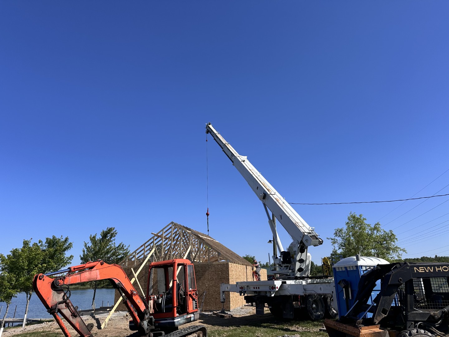 crane setting roof trusses on lakeside building
